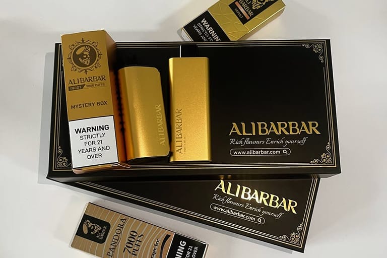 A collection of Ali Barbar products including a vape device, nicotine gum, and nicotine pouches, arranged elegantly.