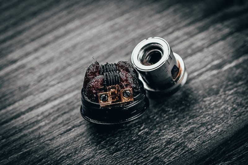 A comparison image showing a pristine, new vape coil next to a heavily gunked and burnt coil, illustrating the impact of sweet e-liquids.