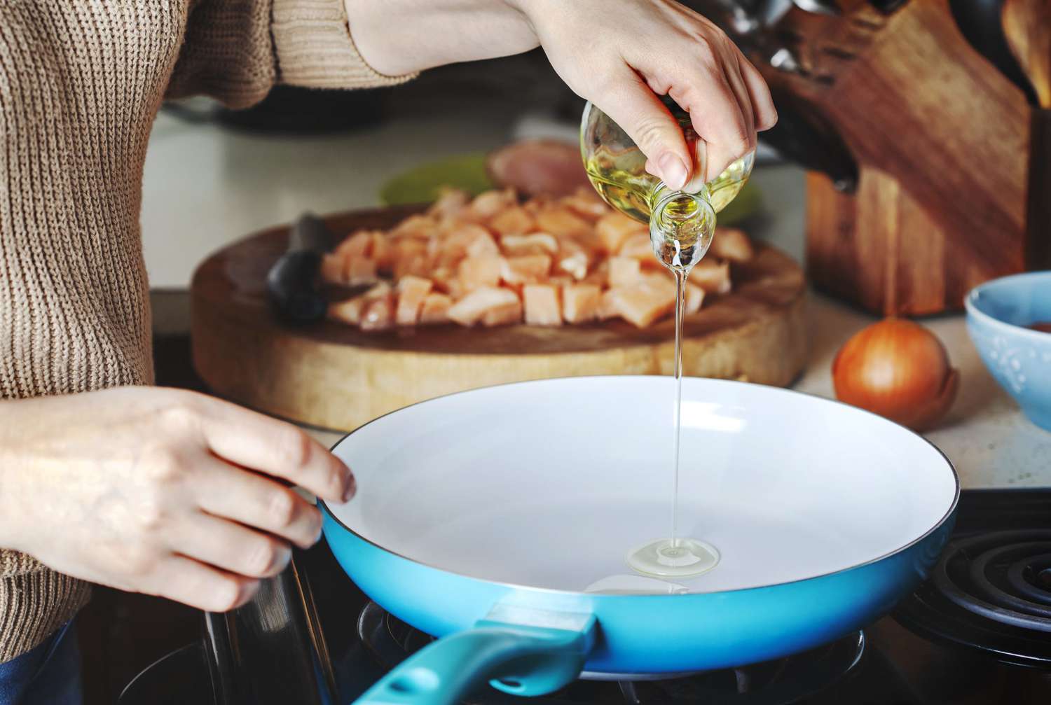 Water droplets violently splashing and sizzling on a hot frying pan coated in cooking oil, illustrating the chaotic boiling action of e-liquid during vape spitback.