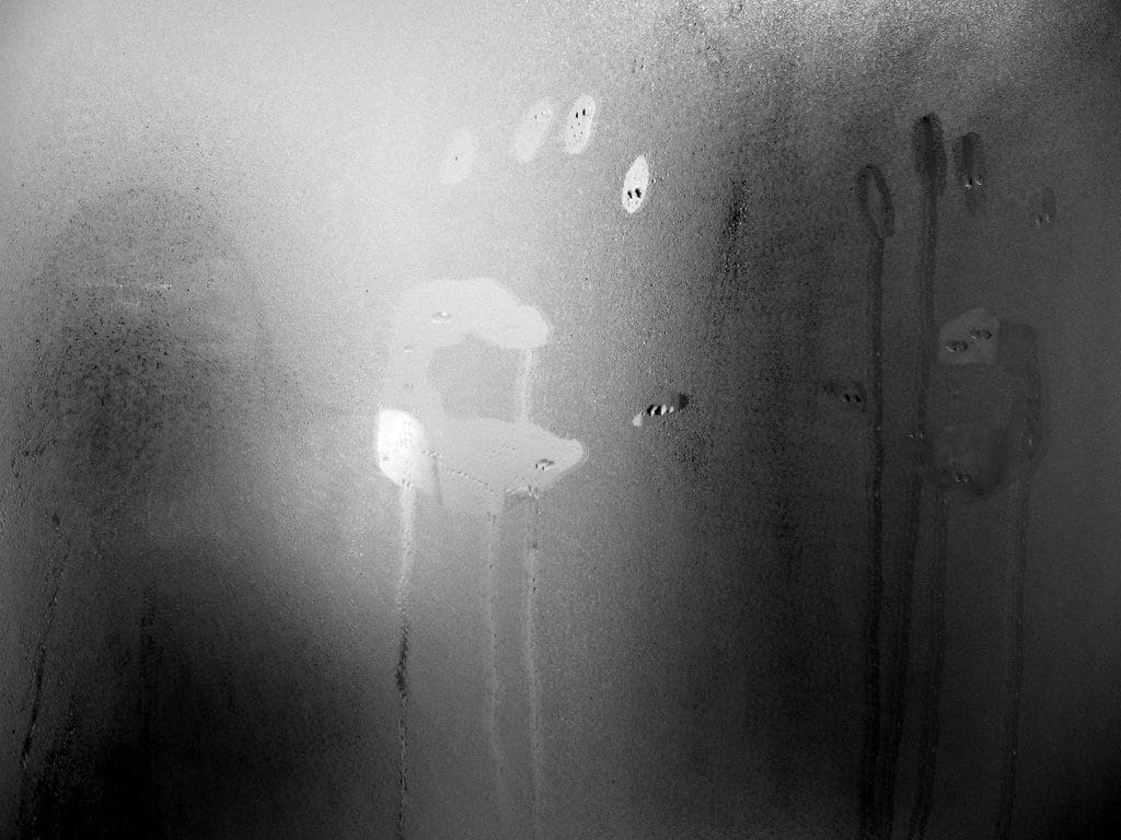Steam condensing on a cold bathroom mirror, illustrating the physical reaction of vapor condensation.
