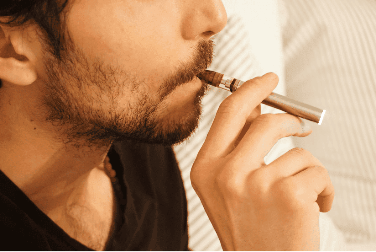 A person demonstrating a slow, steady, and gentle inhalation from a vape device for a smoother experience.