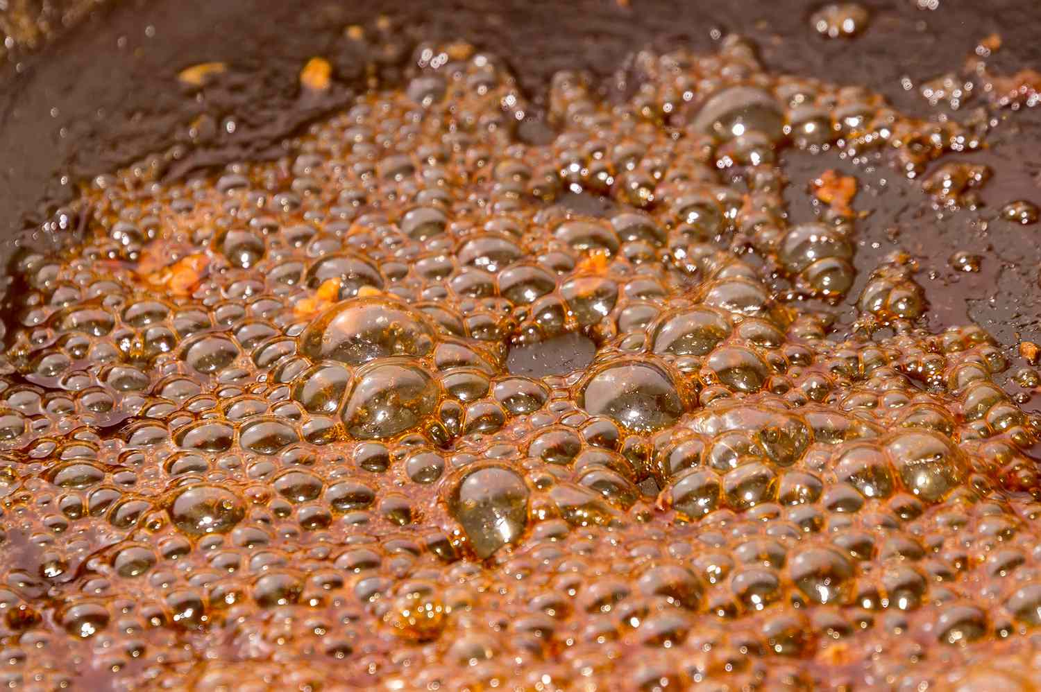 A saucepan on a stove with sugar water boiling, showing caramelized sugar residue forming a hard crust at the bottom, analogous to coil gunk.